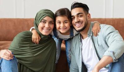 Young mum and dad with child between them smiling at the camera