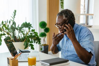 Man sitting at laptop making a phone call