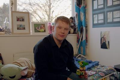 Photograph of a person sitting in a bedroom in shared lives