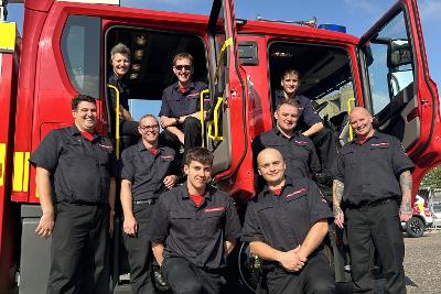 Photograph of Norfolk on-call firefighters sitting in, and standing around, a fire engine