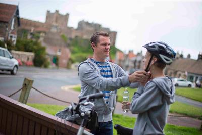 Parent helping child with bicycle helmet