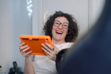 Image of woman smiling and laughing holding a tablet