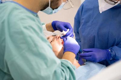 Photograph of a dentist and dental nurse carrying out surgery on a patient