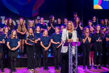 Sara Tough OBE and the Echoes of the East choir on stage