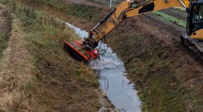 Ditch in a country field being cleared out by a digger